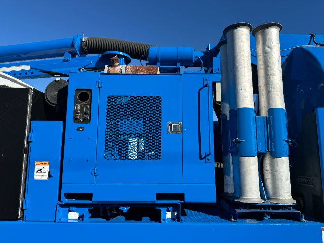 Sterling L7500 vacuum truck engine bay area with blue metal panels, vented door, control panel, and exhaust stacks.
