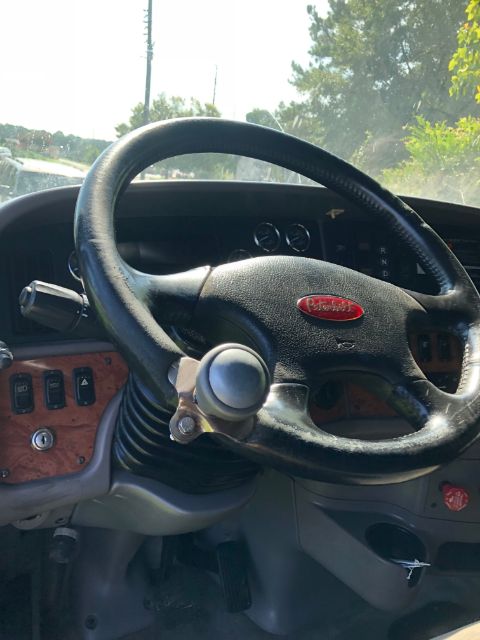 Peterbilt steering wheel with dashboard and controls visible in cab interior.