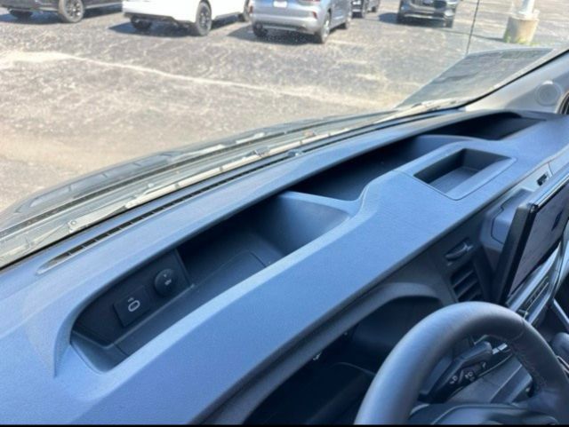 Dashboard and driver-side interior of a 2023 Ford Transit 350 box truck showing cargo area, dashboard shelf, and steering wheel.