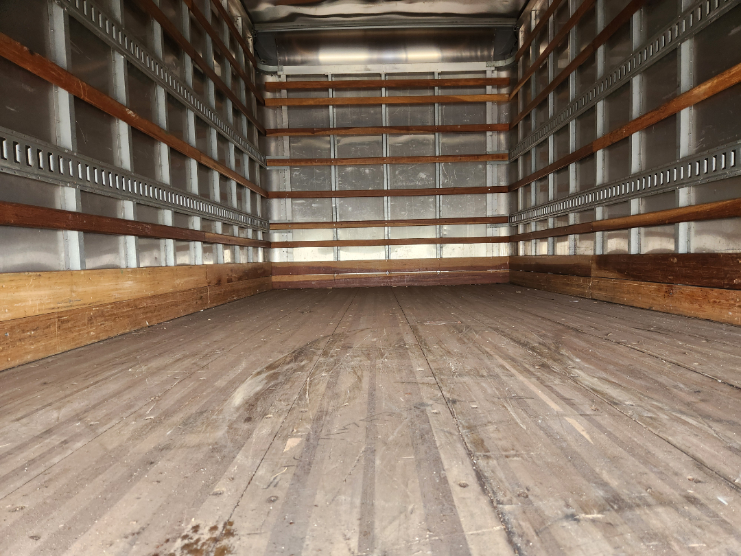 Empty truck cargo area of a 2017 Hino 155 box truck showing wooden side rails and metal walls.