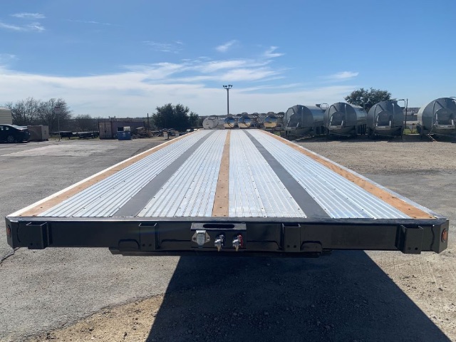 Flatbed trailer rear end with 48ft combo flatbed. Long metal deck with three longitudinal grooves and wooden cleats along edges. Rear coupler area has lights and connectors.