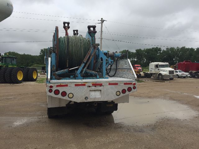 Back of a service/utility truck with a large reel of hose on a metal rack and wiring equipment mounted on a flatbed.