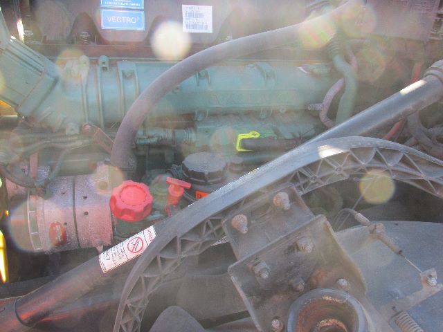 Volvo engine bay in a 2011 Volvo 780 conventional sleeper truck showing red and black fluid caps and engine components.