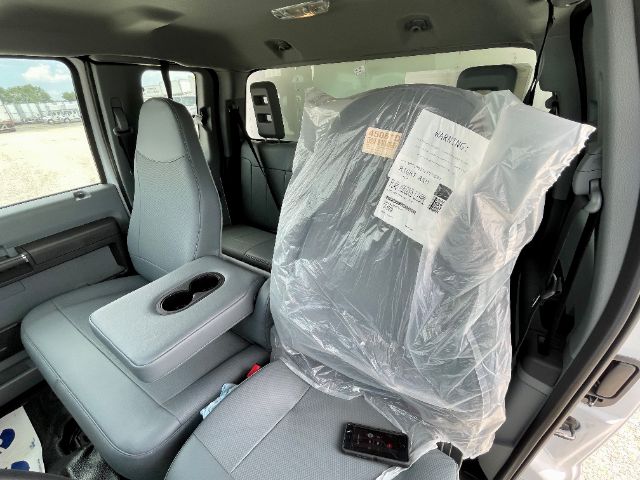 Truck cab interior showing grey fabric seats with center console and plastic-wrapped driver seat in a Ford F-650 moving truck.