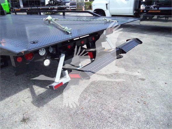 Truck bed with a fold-down ramp and chain; view of rear of a 2023 International CV tow truck in a dealership lot.