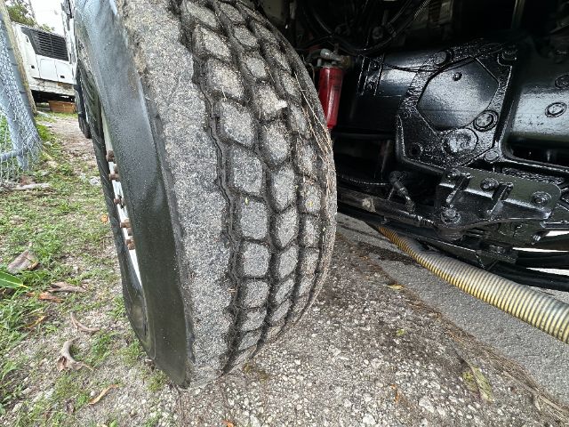 Truck front wheel with rugged tire and undercarriage components visible in a Peterbilt 340 engine bay area.