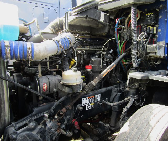 Kenworth T680 engine bay showing various hoses, wiring, and components under the hood.
