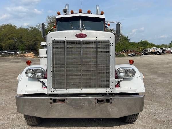 Peterbilt 359 front view showing large square grille, twin round headlights, chrome bumper, white cab with orange marker lights, and Peterbilt emblem.
