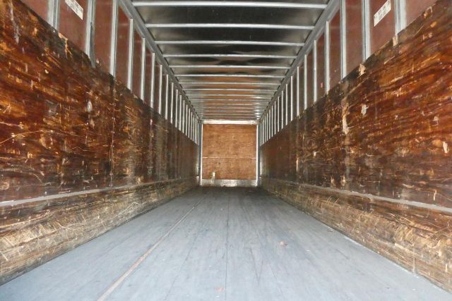 Interior view of a Fruehauf trailer cargo area with wooden side walls and a flat floor.