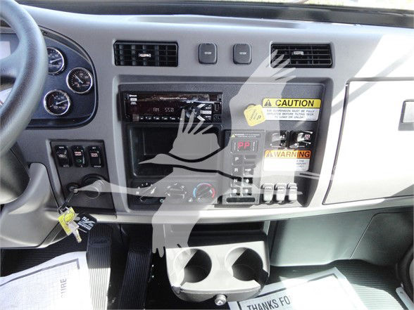 Truck cab dashboard showing stereo receiver, air vents, control switches, and cup holders in a Peterbilt 337 interior.