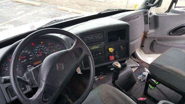 International truck dash with steering wheel, gauges, and gear shift; cab interior visible.