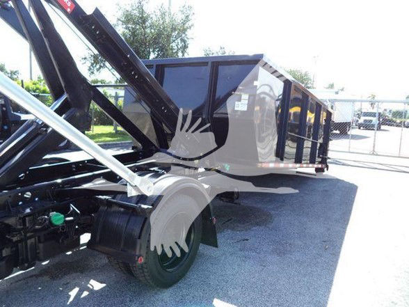 Front-left view of a 2023 Chevrolet Silverado 6500HD chassis with a dump body, showing hydraulic arms and rear wheel, part of a heavy-duty truck.