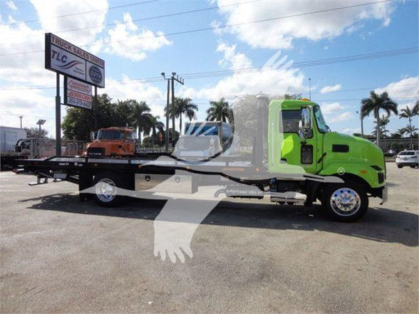 Green 2025 Mack MD6 tow truck with a long flatbed, side view, stock number J04366.