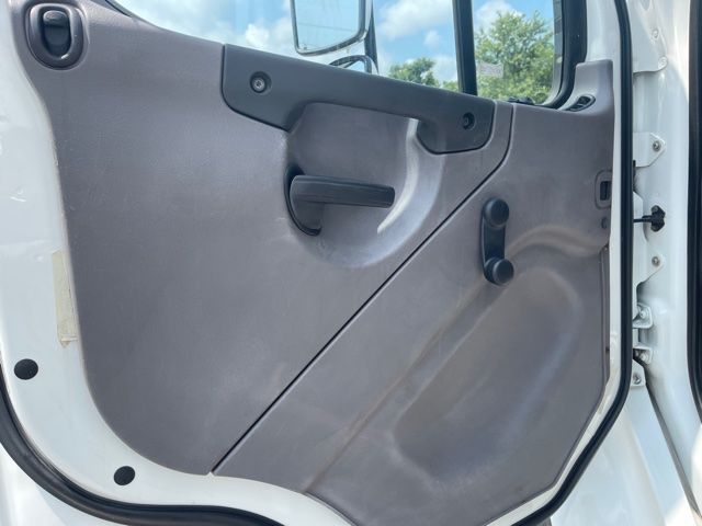 Freightliner M2 truck cab interior door panel showing window crank and armrest.