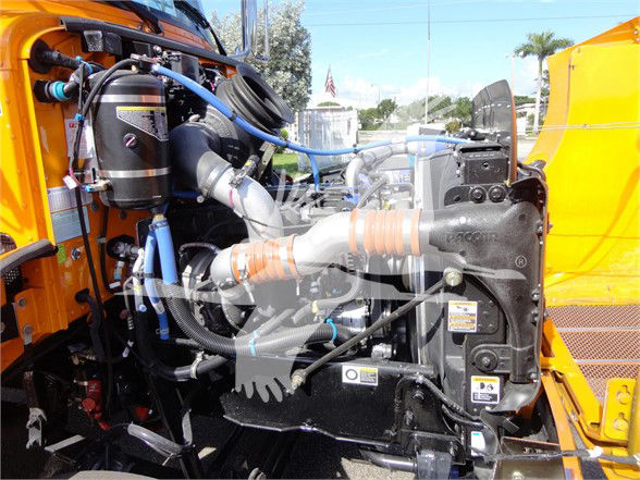 Peterbilt 337 engine bay showing coolant hoses, air intake, and radiator with orange truck cab visible