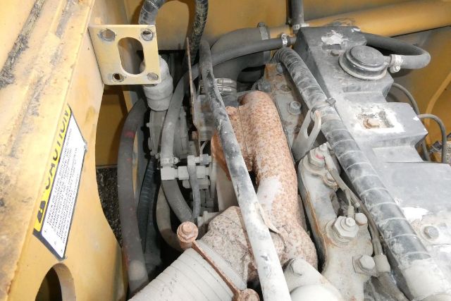 Engine bay of a Grove YB4410 crane showing diesel engine, intake manifold, hoses, and components with rust on exhaust manifold and pulley system.
