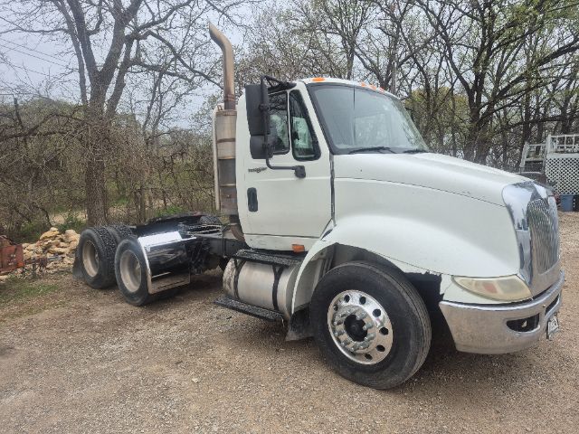 Truck cab and chassis of a 2008 International 8600 with white cab, vertical exhaust, dual rear axles, and chrome fuel tanks.