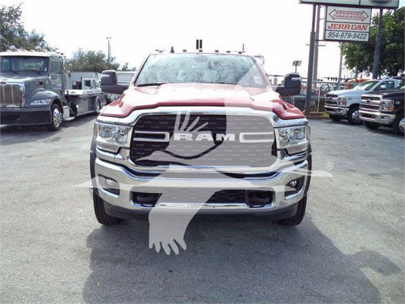 Ram 4500 front view showing chrome grille with RAM logo and headlights, red hood accents, dealership lot in background.