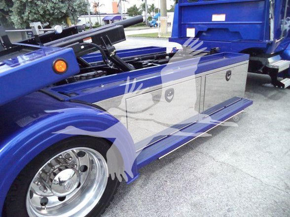 Tow truck side view showing large storage compartments and wheel, with blue paint and polished chrome wheels.