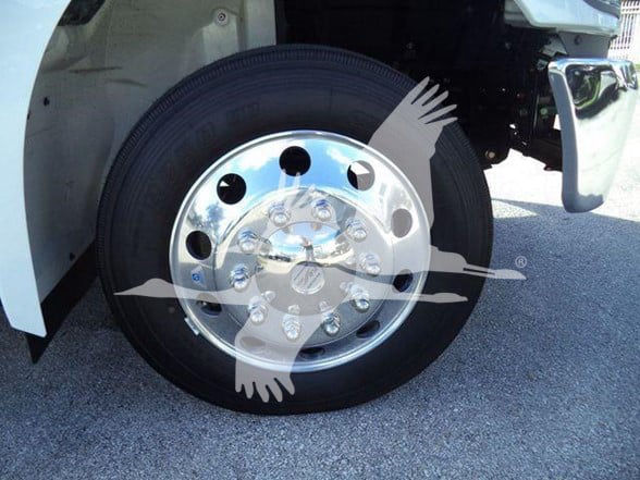 Wheel and chrome hubcap of a Hino 268A tractor-trailer showing polished steel rim with multiple lug nuts.