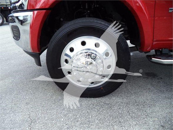 Wheel and tire close-up on a red Ram 5500 truck front, chrome steel wheel with multiple circular holes.