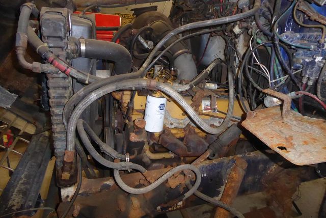 Ford 8000 engine bay showing various hoses, rusted components, and a white filter canister with hoses surrounding it.
