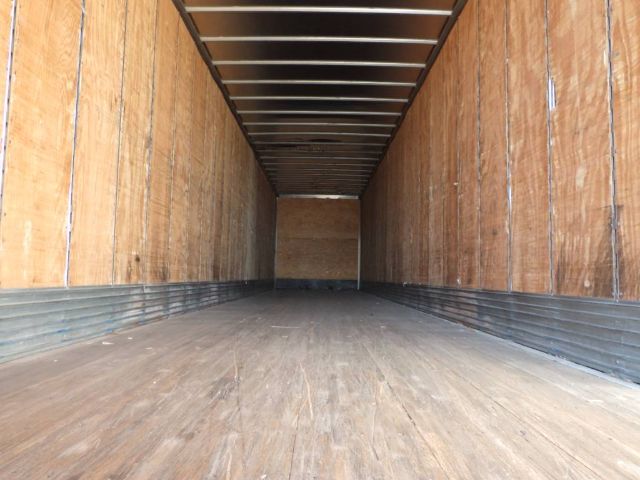 Trailer interior showing empty wooden sidewalls and floor with metal roof beams.