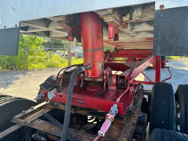 GMC trailer undercarriage with hydraulic landing gear and red frame components; hydraulic hose and valve visible.