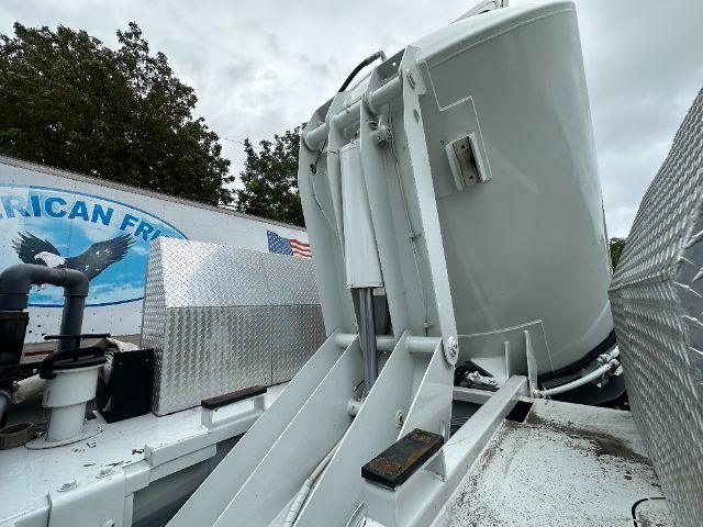 Large gray cab-forward fuel or equipment container on a Freightliner 114SD truck, with metallic diamond plate panels and mounting hardware visible.