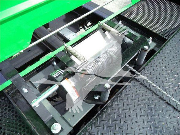 Tow truck hoist mechanism with steel cable and winch on a green Peterbilt 536 showing hydraulic winch and mounting hardware.