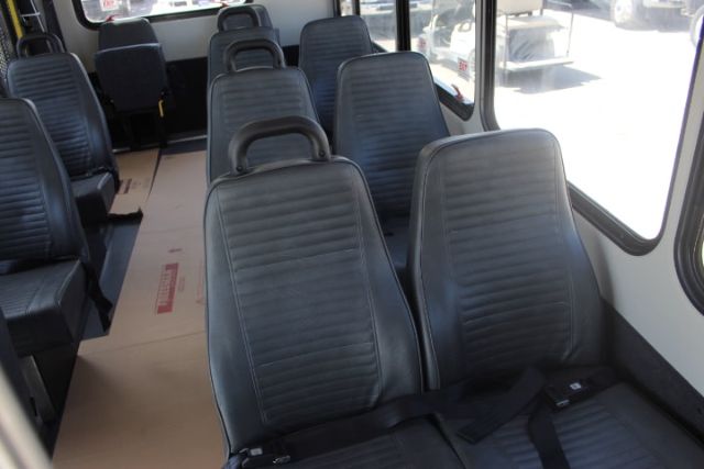 Ford E-450 shuttle bus interior with black vertical ribbed seats and seat belts, front window view.