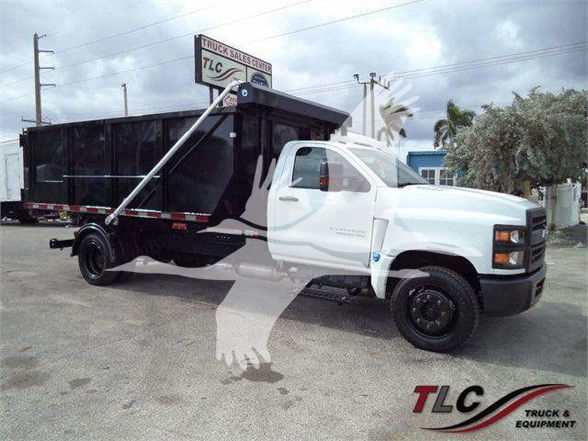 Chevrolet Silverado 6500HD dump truck side view with white cab and black dump bed.