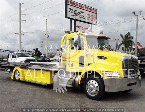 Yellow Peterbilt 337 tow truck cab with flatbed, front chrome bumper, and DOT sign on top. Visible TLC Truck Sales Center sign in background.