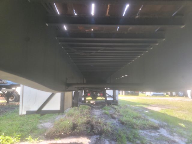 Underneath a flatbed trailer showing the underside frame and support crossmembers.