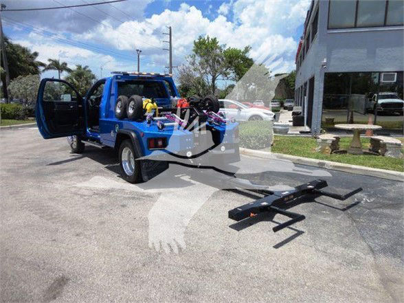 Blue Ram 4500 Tow truck with wheelchair? slide? No, shows a tow truck with a dolly/hook equipment in the bed and a detachable loader on the ground.
