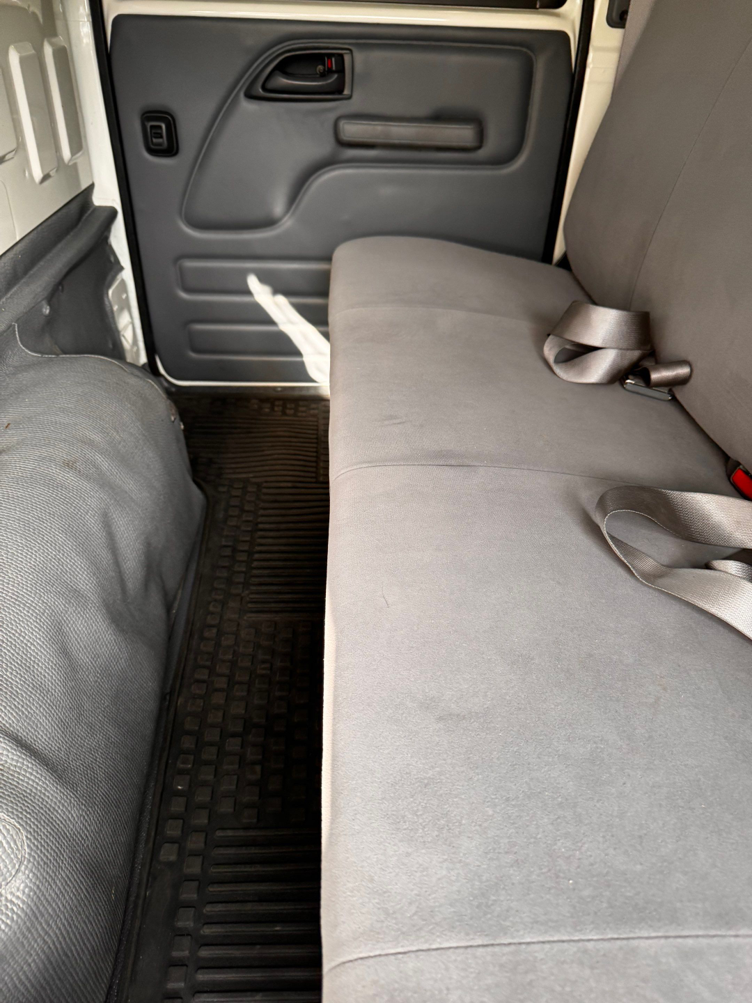 Isuzu NQR interior rear seating area with side door panel and seat belt visible.