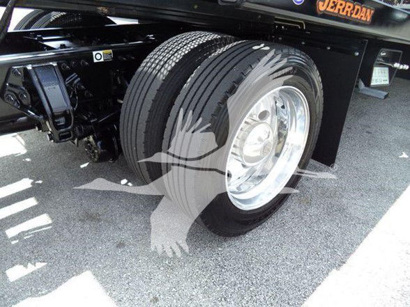 Peterbilt truck rear wheel and suspension showing dual tires and chrome wheel, undercarriage components visible.