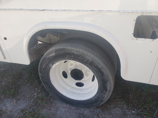 Wheel well of a white Ford F-550 utility truck showing steel wheel and tire.
