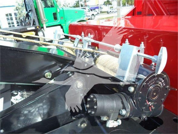 Tow truck component showing winch drum and mounting hardware with hydraulic reel and cables.