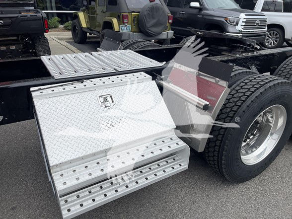 Volvo truck wheel and aluminum diamond plate side step for 2022 Volvo VNL64T740 showing storage boxes and fuel tank area.