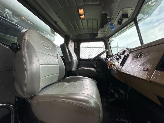 Truck cabin interior of a 2008 Peterbilt 340 showing driver seat, passenger seat, and brown dashboard; overhead cabin lights and steering column visible.