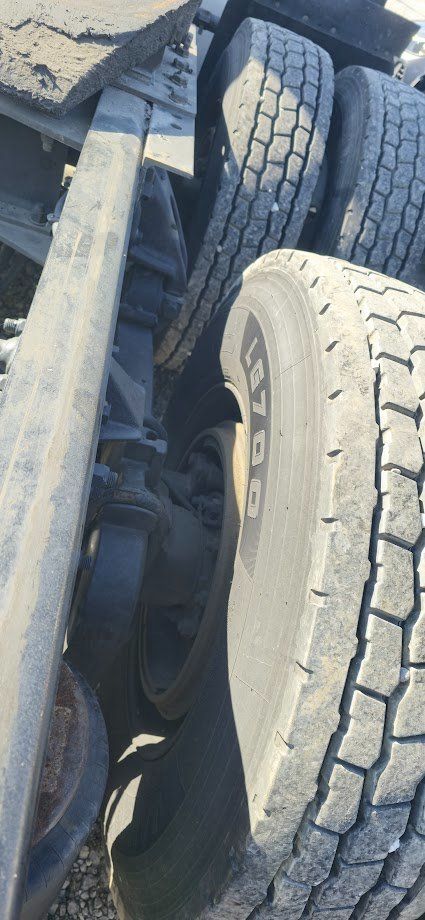 Kenworth heavy haul truck wheel and suspension close-up showing dual rear tires and chassis components.