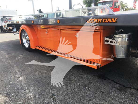 Peterbilt 337 tow truck bed side with bright orange storage cabinets, graphic logo Jerr-Dan on top edge, chrome wheels, rear diesel tank and tools.