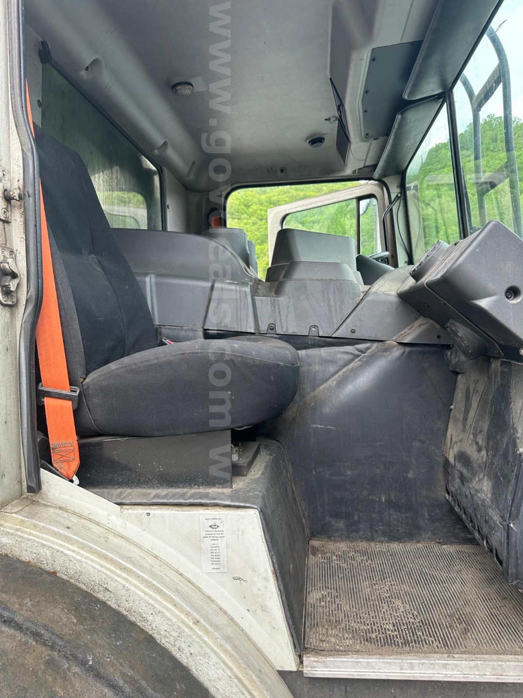 Cab interior of 2017 Mack MRU613 showing driver seat, steering column, dashboard, and entry step. Passenger seat and overhead panels visible.