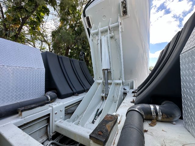 Truck chassis interior showing vertical vacuum tank mount and hoses with metal diamond plate panels.