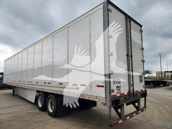 Wabash trailer with aluminum side panels and rear doors, seen from left-rear angle in a parking lot.