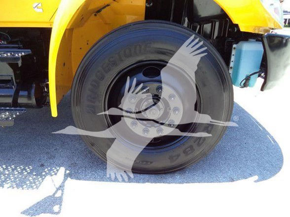 Bridgestone tire mounted on a wheel of a yellow truck visible in wheel well; some vehicle branding watermark across image.