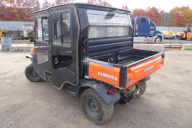 Kubota RTV-X1140 utility vehicle with orange cargo bed, black cab, rear view showing cargo bed and tires.