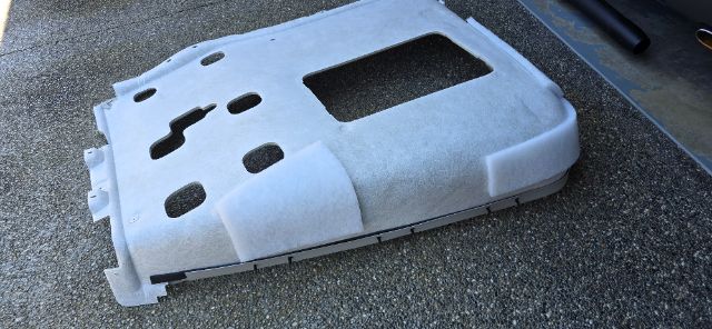 Truck part cover or skid plate with cutouts and foam padding on a textured surface.