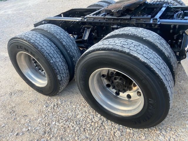 Rear dual-axle truck tires and wheels on a Mack CXU613 chassis showing dual rear axles and part of the frame.